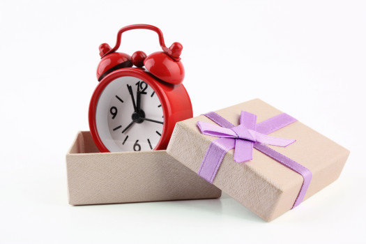 Red alarm clock in a cream box with lilac ribbon